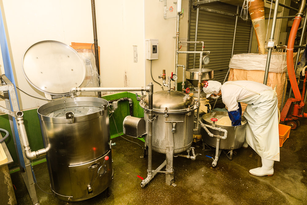 大規模な製造ラインの脇に備えられた専用の調理機材（右から磨砕機、煮釜、搾り機）。すべて手作業での豆腐づくりを週3回、早朝から行います。